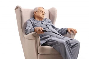 Äldre man som sitter och somnar i en soffa